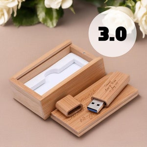 May include: A wooden USB flash drive and box set. The USB drive has a blue USB connector and is engraved with text. The box is open, revealing a white interior. The text "3.0" is in a white circle in the background.