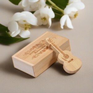 May include: A wooden box with the text "Lexan Swift Photographer" engraved on the top. A wooden guitar-shaped USB drive is next to the box.