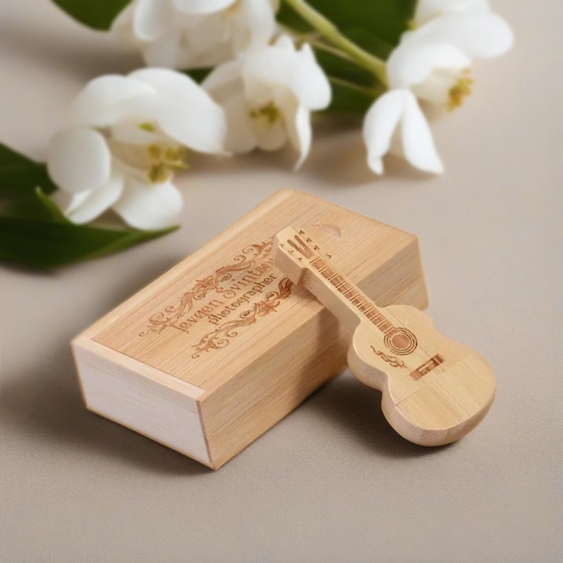 May include: A wooden box with the text "Lexan Swift Photographer" engraved on the top. A wooden guitar-shaped USB drive is next to the box.
