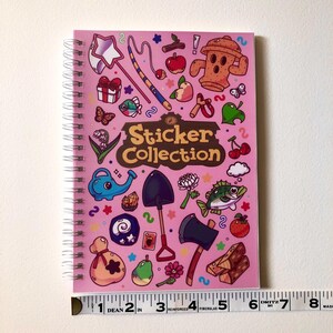 Image showcasing the width of the sticker book using a fabric ruler. It is roughly 5.83 inches wide.