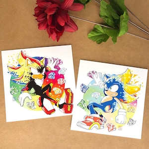 May include: Two illustrations of Sonic the Hedgehog characters, Shadow and Sonic, in their Super forms. Both characters are surrounded by colorful gems and have a yellow and red color scheme.