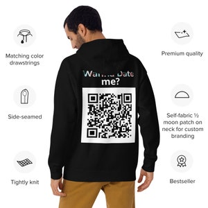 Peut inclure: Sweat-shirt à capuche noir avec un code QR blanc et le texte "Wanna Date me?" imprimé au dos. Le sweat-shirt a un patch en tissu auto-adhésif en forme de demi-lune sur le cou pour un marquage personnalisé.