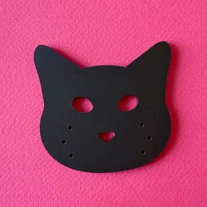 May include: Black felt cat mask with cut-out eyes, nose, and whiskers. The mask has four small holes on each side.