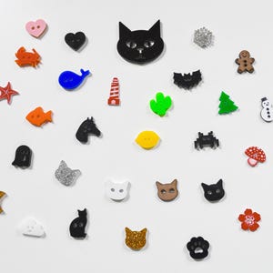May include: Assortment of colorful and glittery buttons in various shapes, including animals, hearts, stars, and geometric designs.