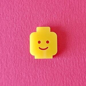 May include: A yellow plastic LEGO minifigure head with a smiling face.