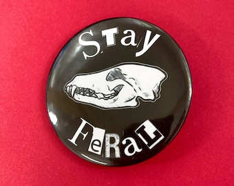 May include: Black and white button with the text "Stay Feral" and a skull of an animal with sharp teeth. 