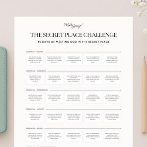 Può includere: Una Bibbia verde chiaro accanto a una guida stampata intitolata "The Secret Place Challenge" con il testo "30 Days of Meeting God in the Secret Place". Sono presenti anche una matita e un piccolo vaso di fiori bianchi.