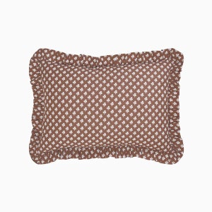 May include: A brown pillow with a white clover pattern and a ruffled edge.