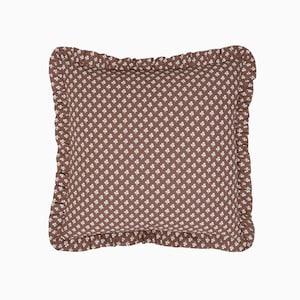 May include: A brown square pillow with a white floral pattern and a ruffled border.