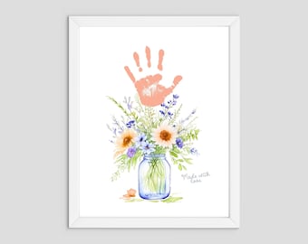 May include: A watercolor painting of a handprint in a peach color, with a bouquet of flowers in a blue mason jar. The flowers are a mix of sunflowers, lavender, and other wildflowers. The text "Made with Love" is written below the jar.