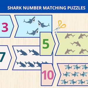 以下が含まれることがあります： 上部に「SHARK NUMBER MATCHING PUZZLES」というテキストが記載されたサメの数字合わせパズル。セットには数字の3、5、7、10が書かれた長方形のカードと、それに対応するサメのイラストが含まれています。黄色いハサミが描かれています。