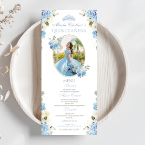 May include: A Quinceañera menu card with a light blue floral design. The menu features a photo of a woman in a blue gown. The menu includes the words "Maria Cristina's Quinceañera" and the date "SAT. FEBRUARY 21, 2029".