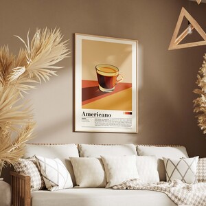 May include: A poster with a minimalist illustration of a cup of coffee with the word "Americano" printed below. The poster is framed in a light wood frame and hangs on a brown wall.