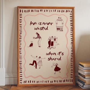 May include: A framed art print with a light beige background and a brown wooden frame. The print features the text "love is never wasted when it's shared" with illustrations of people and animals in a reddish-brown color.