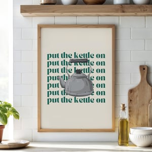 Könnte beinhalten: Ein gerahmter Druck mit grünem Hintergrund und dem Text "put the kettle on", der mehrmals wiederholt wird. Eine silberne Teekanne ist mittig im Druck platziert.