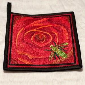 May include: Red and orange embroidered rose with a green bee on a black square pot holder with a hanging loop.