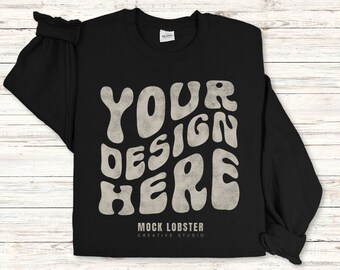 May include: Black long-sleeve shirt with a white graphic that says "YOUR DESIGN HERE" in a retro font. The shirt also has the text "MOCK LOBSTER CREATIVE STUDIO" at the bottom.