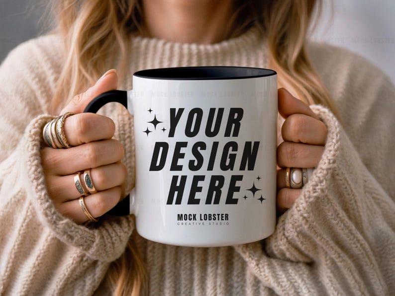 May include: A white ceramic mug with a black rim and handle. The mug has the text "YOUR DESIGN HERE" in black lettering and the words "MOCK LOBSTER CREATIVE STUDIO" in smaller black lettering.