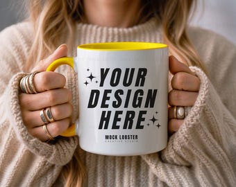 May include: A white ceramic mug with a yellow rim and handle. The mug has black text that says "YOUR DESIGN HERE" and "MOCK LOBSTER CREATIVE STUDIO".