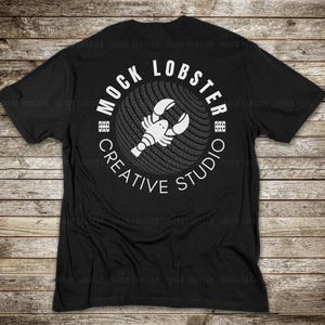 May include: Black t-shirt with a white circle graphic featuring a lobster and the text "Mock Lobster Creative Studio".
