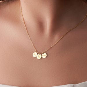 May include: Gold necklace with three small round pendants. The pendants are engraved with the names "Jack", a heart symbol, and "Anna".