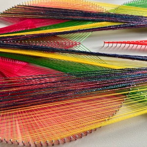 May include: A colorful string art piece with red, yellow, green, and purple threads woven together in a geometric pattern.
