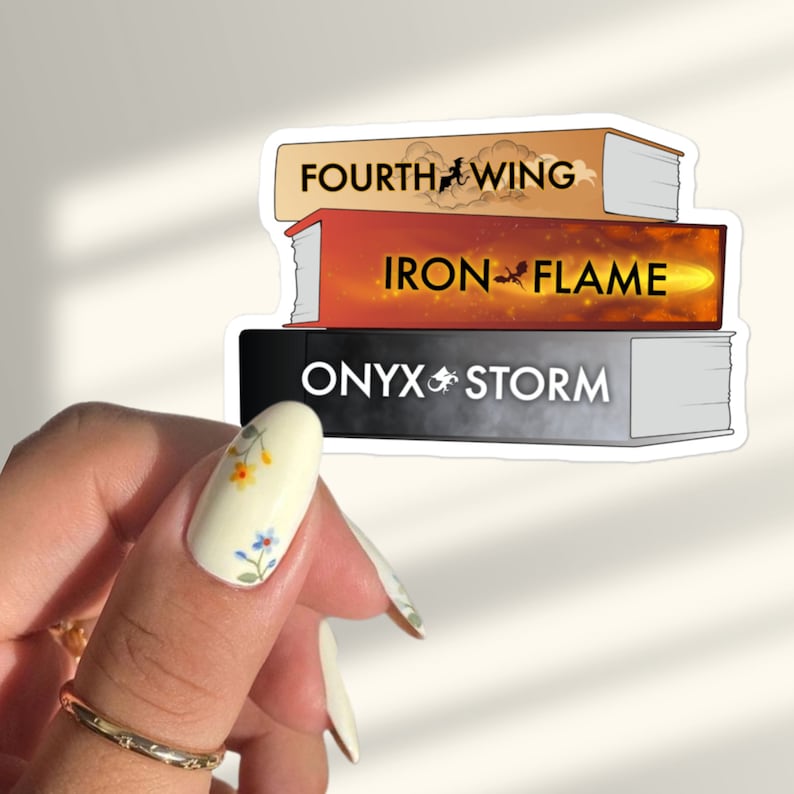 Op de afbeelding: Een sticker met een stapel van drie boeken met de titels "Fourth Wing", "Iron Flame" en "Onyx Storm". Elke boektitel staat in een ander lettertype en kleur, en de sticker is ontworpen om eruit te zien als een stapel boeken.