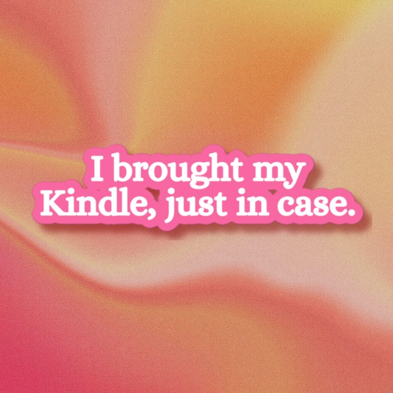 May include: A die-cut sticker featuring the white text I brought my Kindle, just in case. The lettering is outlined in a bold, vibrant pink color, creating a clear and readable message against the soft, gradient orange and pink background.