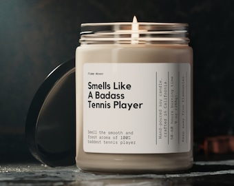 May include: A clear glass jar candle with a white label that reads "Smells Like A Badass Tennis Player". The candle is hand-poured soy and crafted in California. It has a burn time of 50-60 hours and is 9 ounces.