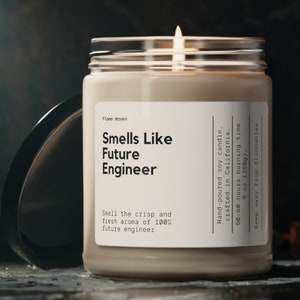 Könnte beinhalten: Eine durchsichtige Glaskerze in einem Glas mit einem weißen Etikett, auf dem "Smells Like Future Engineer" steht. Das Etikett enthält auch den Text "Handgegossene Sojawachskerze, hergestellt in Kalifornien. Brenndauer: 50-60 Stunden 9 oz (255 g)".