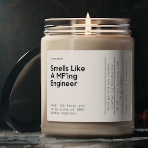 Pode incluir: Uma vela de vidro num frasco com um rótulo branco que diz "Smells Like A MF'ing Engineer". A vela é de soja derretida à mão e feita na Califórnia. Tem um tempo de queima de 50 a 60 horas e pesa 255 g.
