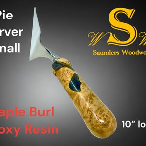 May include: A small pie server with a stainless steel blade and a maple burl handle with epoxy resin accents. The handle is 10 inches long and features the text "Pie Server Small" and "Maple Burl Epoxy Resin". The Saunders Woodwork logo is also visible.