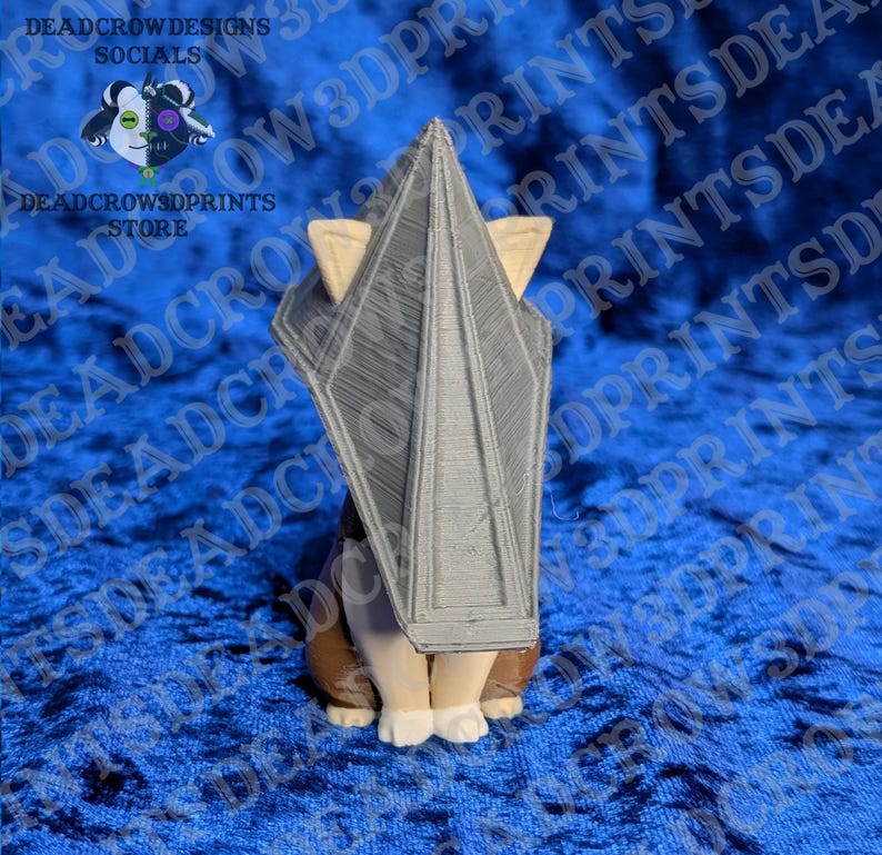 May include: A 3D printed figurine of a creature wearing a large, grey, triangular pyramid-shaped headpiece. The figure has light-colored paws and brown lower body sections, with the pyramid structure featuring visible horizontal layer lines.