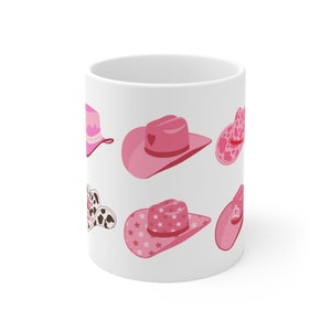 Puede incluir: Taza de cerámica blanca con un patrón de sombrero de vaquero rosa y blanco. Los sombreros tienen diferentes diseños, incluyendo estrellas, corazones y lunares.