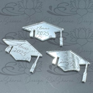 May include: Three silver mirror graduation caps with the name "Anne" and the year "2025" engraved on each.