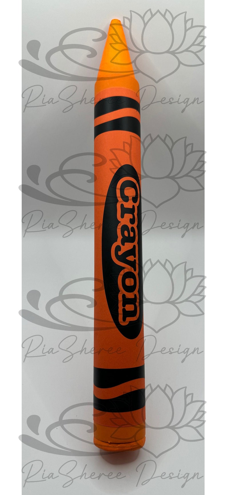 A large fake orange crayon with black lettering that says 'Crayon.’