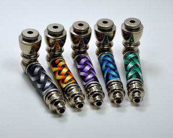 May include: Five metal smoking pipes with different coloured Celtic knot designs. The pipes are silver with a shiny finish.