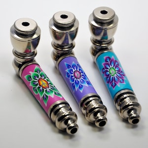 May include: Three metal pipes with colourful floral designs. The pipes are silver with a pink, purple, and blue floral design.