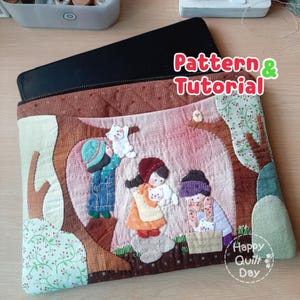 May include: A quilted tablet sleeve with a zipper closure. The sleeve features an applique design of children with cats in a forest scene. The text "Pattern & Tutorial" and "Happy Quilt Day" are visible on the sleeve.