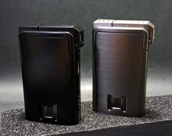 May include: Two rectangular lighters, one black and one gunmetal, are displayed side-by-side. The lighters have a sleek, minimalist design with a textured finish. The base of each lighter features a rectangular cutout.