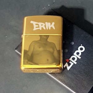 May include: Gold lighter with a photo of a person and the name "ERIK" engraved on the front.