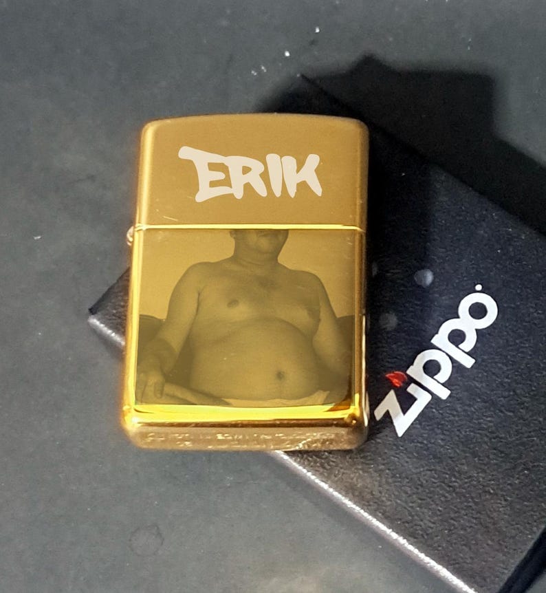 May include: Gold lighter with a photo of a person and the name "ERIK" engraved on the front.