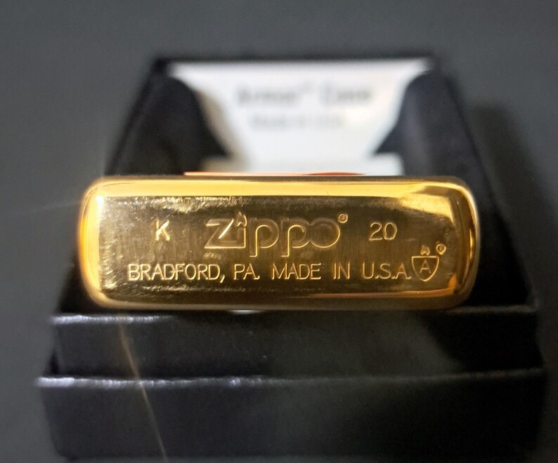 May include: Gold-colored Zippo lighter with the text "K Zippo 20 Bradford, PA. Made in U.S.A." on the bottom.