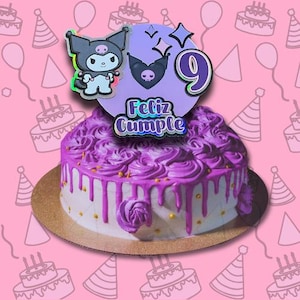 May include: Purple and white birthday cake with a black and white cartoon character topper. The cake is decorated with purple frosting and gold sprinkles. The topper says "Feliz Cumple".