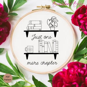 Peut inclure: Broderie en noir et blanc sur un cercle de broderie représentant une étagère avec des livres, une plante en pot, une tasse et le texte "Just one more chapter".