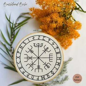 Op de afbeelding: Een witte borduurring met een zwart-wit ontwerp van een kompas met runen rond de buitenkant. De tekst "PDF Pattern" staat in de rechterbenedenhoek van de afbeelding.