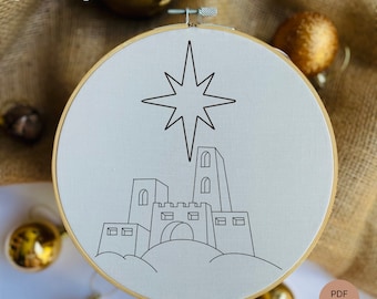 May include: A white embroidery hoop with a black line drawing of a star and a building with a pointed roof. The text "Bushland Boho" is in the upper left corner of the image. The text "PDF Pattern" is in the lower right corner of the image.