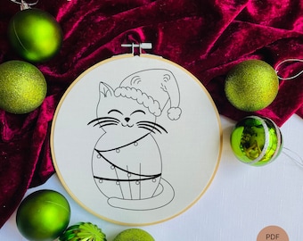 May include: Black and white line art embroidery pattern of a cat wearing a Santa hat and wrapped in Christmas lights. The pattern is on a white background and is surrounded by green ornaments.