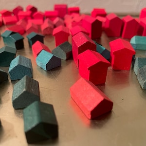 May include: A collection of small wooden houses in red and green colors. The houses are arranged in a random pattern on a silver surface.