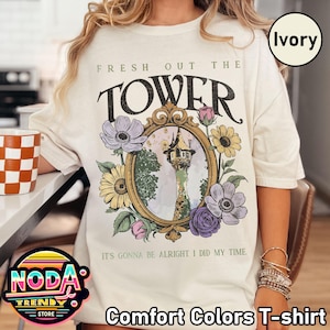 May include: Ivory Comfort Colors T-shirt with the text "FRESH OUT THE TOWER". The shirt features a floral design around a tower illustration. The text "IT'S GONNA BE ALRIGHT I DID MY TIME" is also printed on the shirt.